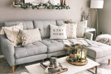 a pretty boho living room with a grey sofa, a white table, layered rugs, neutral tables, some candles and an artwork