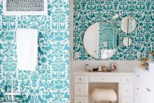 a quirky bathroom with walls covered with flora and fauna turquoise wallpaper, white furniture and appliances looks fun
