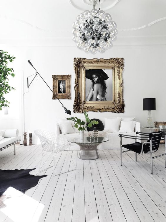 a refined and chic living room with white walls, a whitewashed floor, black and white furniture and refined artworks