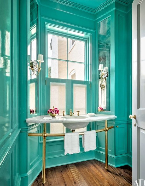 A refined vintage bathroom all painted in turquoise, with a free standing sink and touches of gold looks very chic