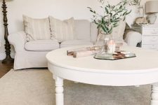 a white shabby chic living room with a creamy Ektorp sofa, a low round table, a nightstand, floor and table lamps
