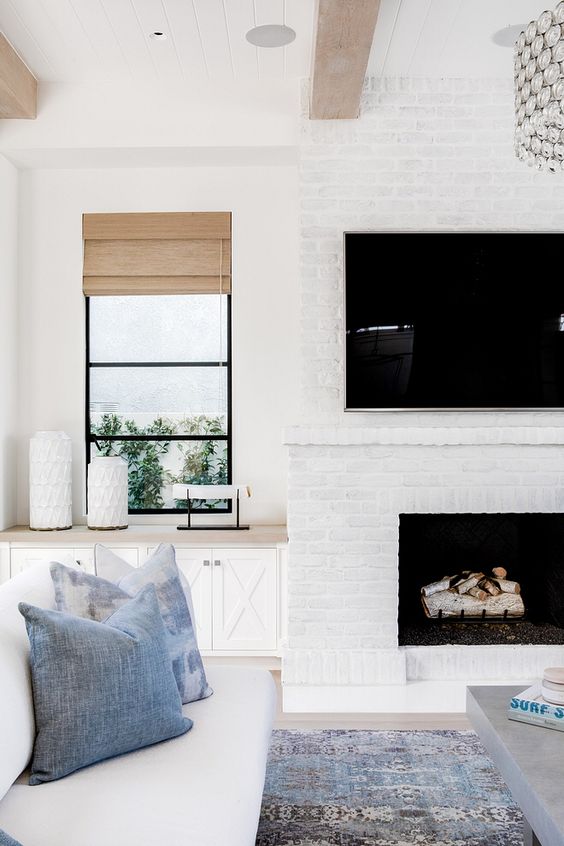 a whitewashed brick fireplace brings coziness to the neutral coastal living room and makes it cozier