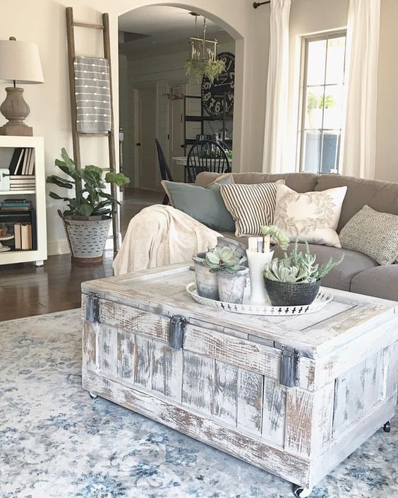 a whitewashed chest as a coffee table on casters and a tray with potted plants for finishing off a farmhouse living room