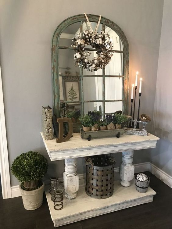 a whitewashed console table, potted plants, a cotton wreath, candles and candleholders for a refined vintage entryway