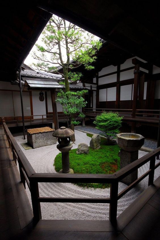 a Japanese courtyard with grass, stone larnterns and a stone water tub, low trees looks very refreshing