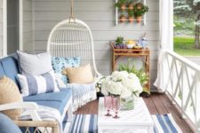 a bright and welcoming summer porch with rattan furniture, a wall garden, a hanging chair and some blue textiles