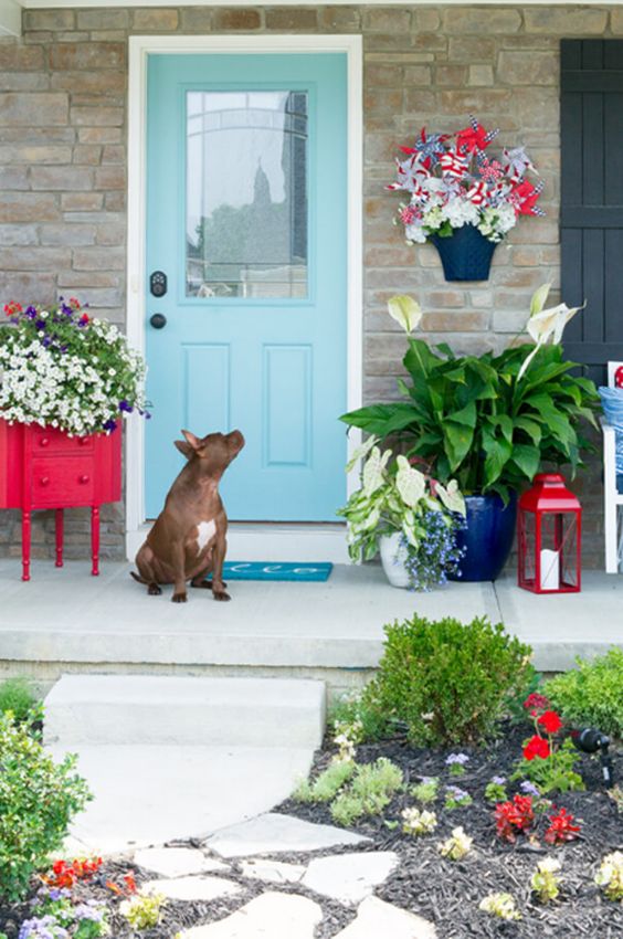 a bright summer porch with a sideboard turned in a planter, bright potted blooms and a red candle lantern