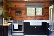 a cabin kitchen clad with stained wood, with dark cabinets, wooden and stone countertops