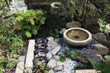 a chic Japanese front yard with pebbles, rocks, a stone bowl with a fountain, trees, greenery and bamboo