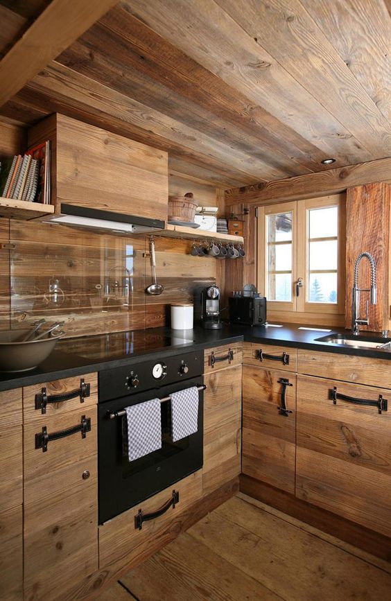 a contemporary chalet kitchen fully done with light stained wood, with a glass backsplash and black leather handles