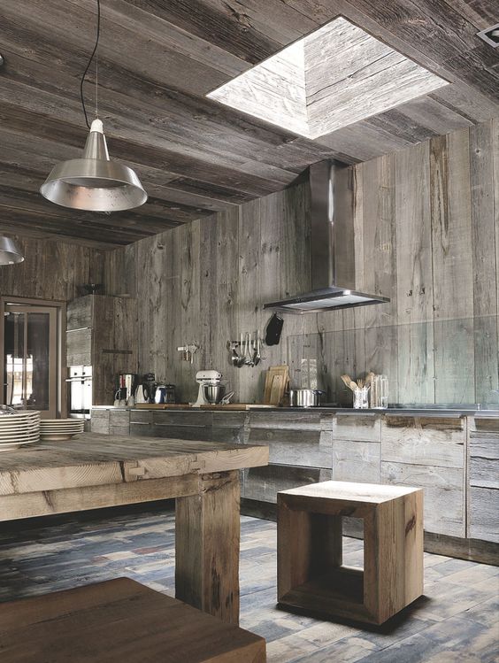 a contemporary chalet kitchen with reclaimed wooden walls and cabinets, with matching furniture and stainless steel appliances