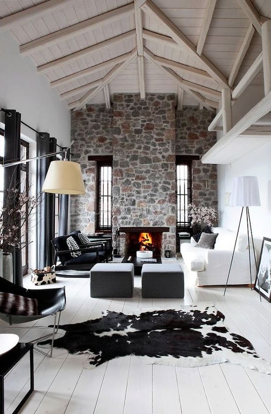 a contemporary living room with white walls, a whitewashed wooden ceiling, a stone clad fireplace and cool furniture