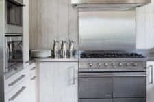 a contemporary white chalet kitchen all clad with wood, with stainless steel appliances is laconic and chic