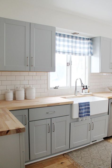 a cozy welcoming dove grey kitchen with light stained butcherblock countertops and touches of plaid