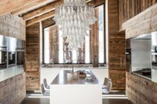 a gorgeous chalet kitchen with reclaimed wooden walls, ceiling and furniture, with a tassel chandelier and a white kitchen island