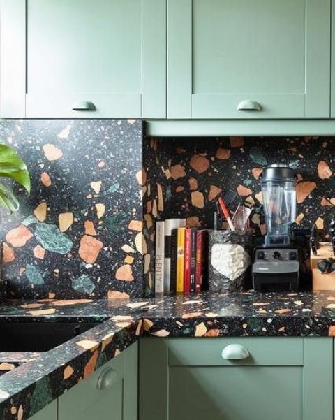 a green kitchen with bold terrazzo countertops and a backsplash is a fun and bold idea to add drama to the space
