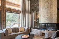 a jaw-dropping chalet living room with all wood around, a stone wall, a catchy fireplace, modern furniture and hanging lamps