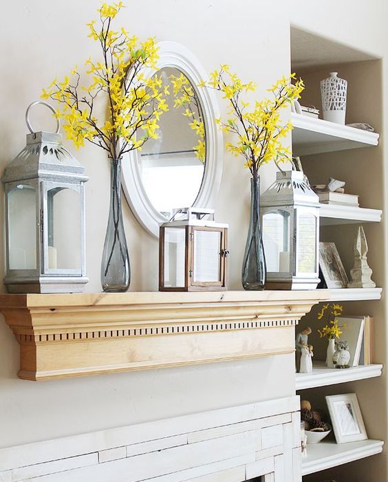 a laconic vintage summer mantel with blooming branches, candle lanterns and a mirror