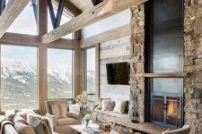 a lodge living room with a faux stone wall with a fireplace, neutral furniture and glazed walls plus wooden beams