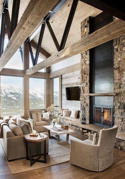 a lodge living room with a faux stone wall with a fireplace, neutral furniture and glazed walls plus wooden beams