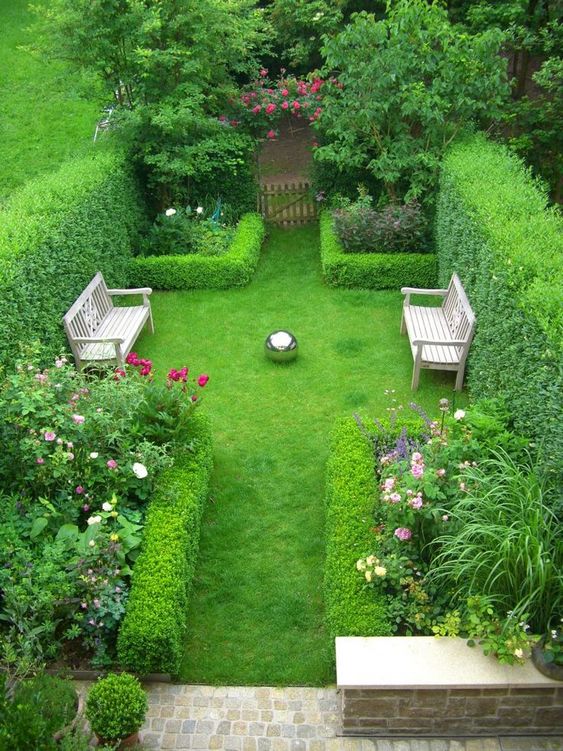 a lush townhouse garden with much greenery, living walls framing the flower beds, wooden benches and some stone