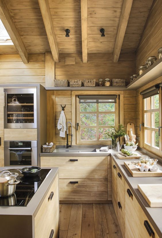 a minimalist chalet kitchen fully done with light-colored wood, with concrete countertops and wooden beams on the ceiling