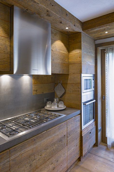 a minimalist chalet kitchen with sleek wooden cabinets and walls, concrete countertops and staineless steel appliances