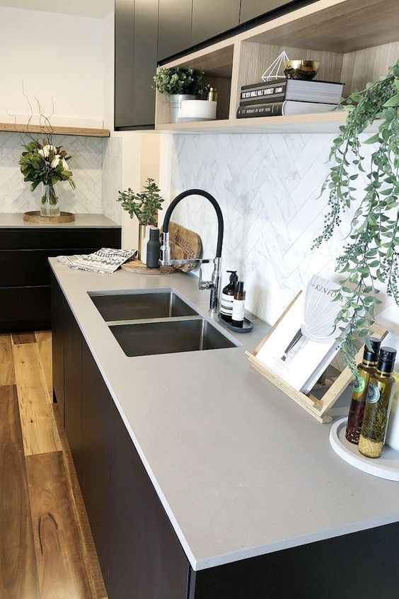 a minimalist kitchen with black cabinets, concrete countertops and a white marble tile backsplash