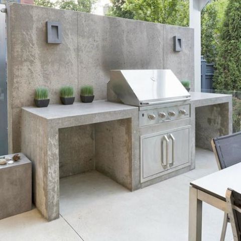 a minimalist outdoor grill zone of concrete, with a grill and potted greenery to refresh the space