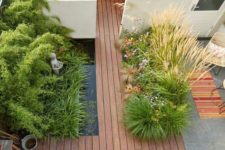 a minimalist townhouse garden with a wooden deck, a pond, planted herbs and grasses and a built-in bench