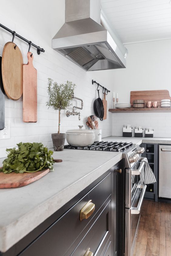 a modern farmhouse kitchen in black, with concrete countertops and stainless steel appliances