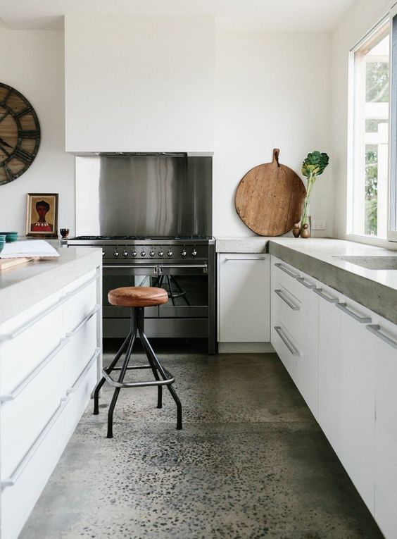 a modern white kitchen with white cabinets, concrete countertops and a large hood