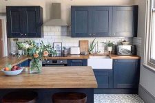 a navy farmhouse kitchen with light stained wooden countertops that soften the look and make it bolder