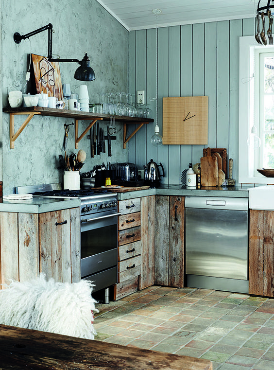 a powder blue chalet kitchen with a plank and plaster wall, reclaimed wooden cabinets and concrete countertops