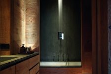 a relaxing chalet bathroom clad with wood, with a rainshower and a bathtub, a built-in vanity and built-in lights