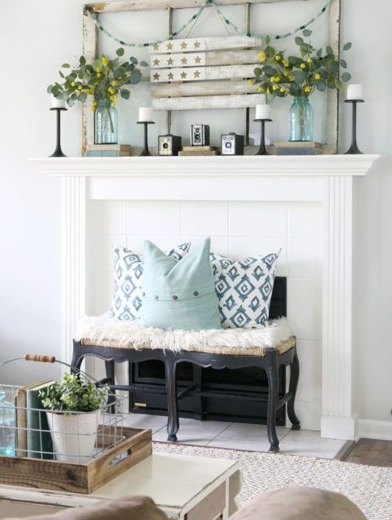 a rustic mantel with a vintage frame and flag, greenery arrangements, candles and vintage books