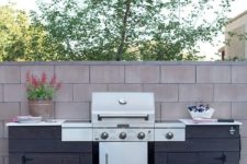 a rustic outdoor bbq area of dark stained wood, with a large grill and some cooking space