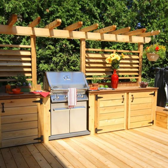 a rustic outdoor bbq area of light stained wood, with much cooking space and a large grill