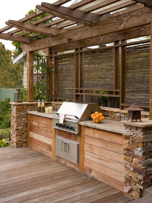 a rustic outdoor bbq zone built of wood and stone, with a cooking countertop and a grill plus lanterns around