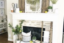 a rustic summer mantel with lemons, greenery, a blooming wreath, shutters, jugs and planters