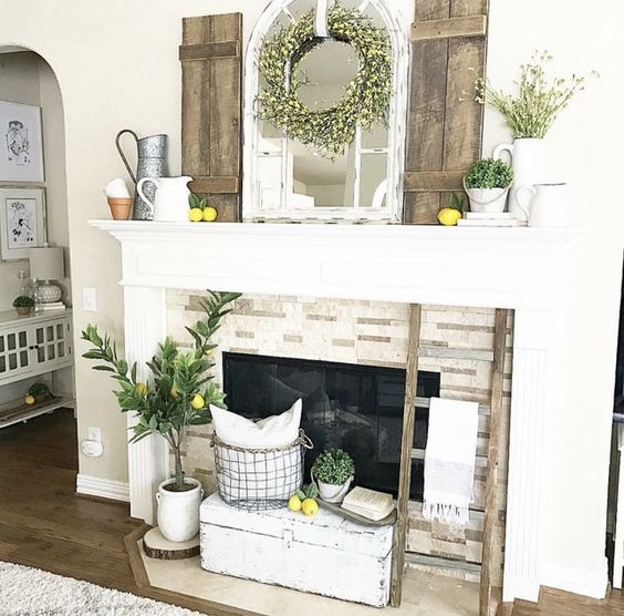 a rustic summer mantel with lemons, greenery, a blooming wreath, shutters, jugs and planters