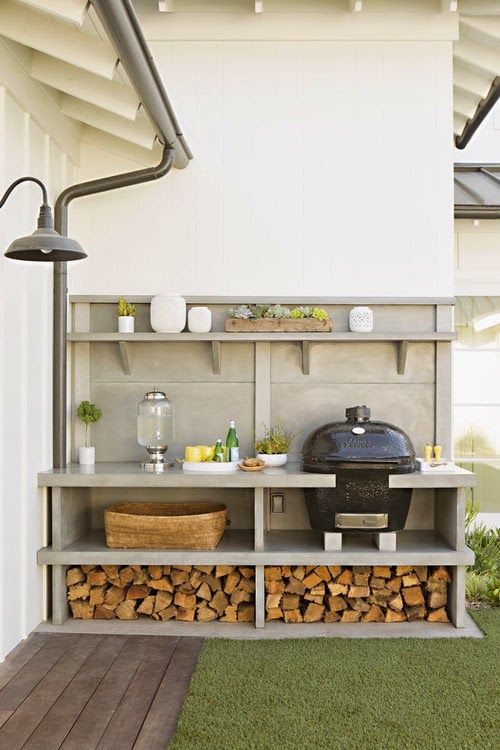 a simple and comfortable outdoor bqq zone with a grill, soem cooking space and firewood stored