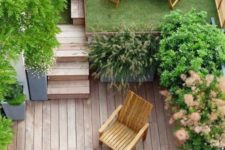 a small townhouse gardne with a wooden deck, a lawn, some potted greenery and wooden furniture