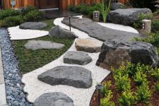 a stylish Japanese front yard with pebbles, rocks, greenery, a rock path and lanterns is a lovely modern decor idea