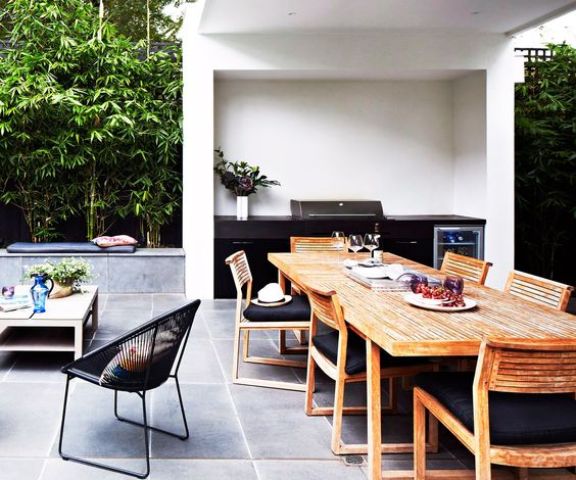 a stylish contemporary dining space done with wooden chairs, a wooden table and blakc upholstery, a black grill next to it