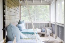 a stylish summer porch with a hanging daybed, a low chair, some neutral and pastel textiles and a boat