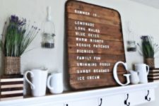 a summer farmhouse mantel with a sign, jugs, lavender, letters and a striped planter