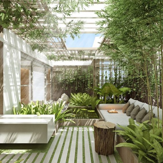 a sunlit inner courtyard with a fireplace and a pond with tropical greenery and a skylight over the space