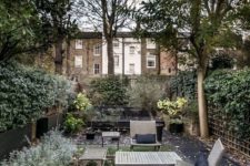 a townhouse garden with a lawn, shrubs and trees, simple wooden furniture and walls around for privacy