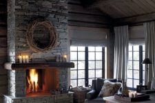a vintage chalet living room with wooden walls and a ceiling, a stone fireplace and faux fur accessories